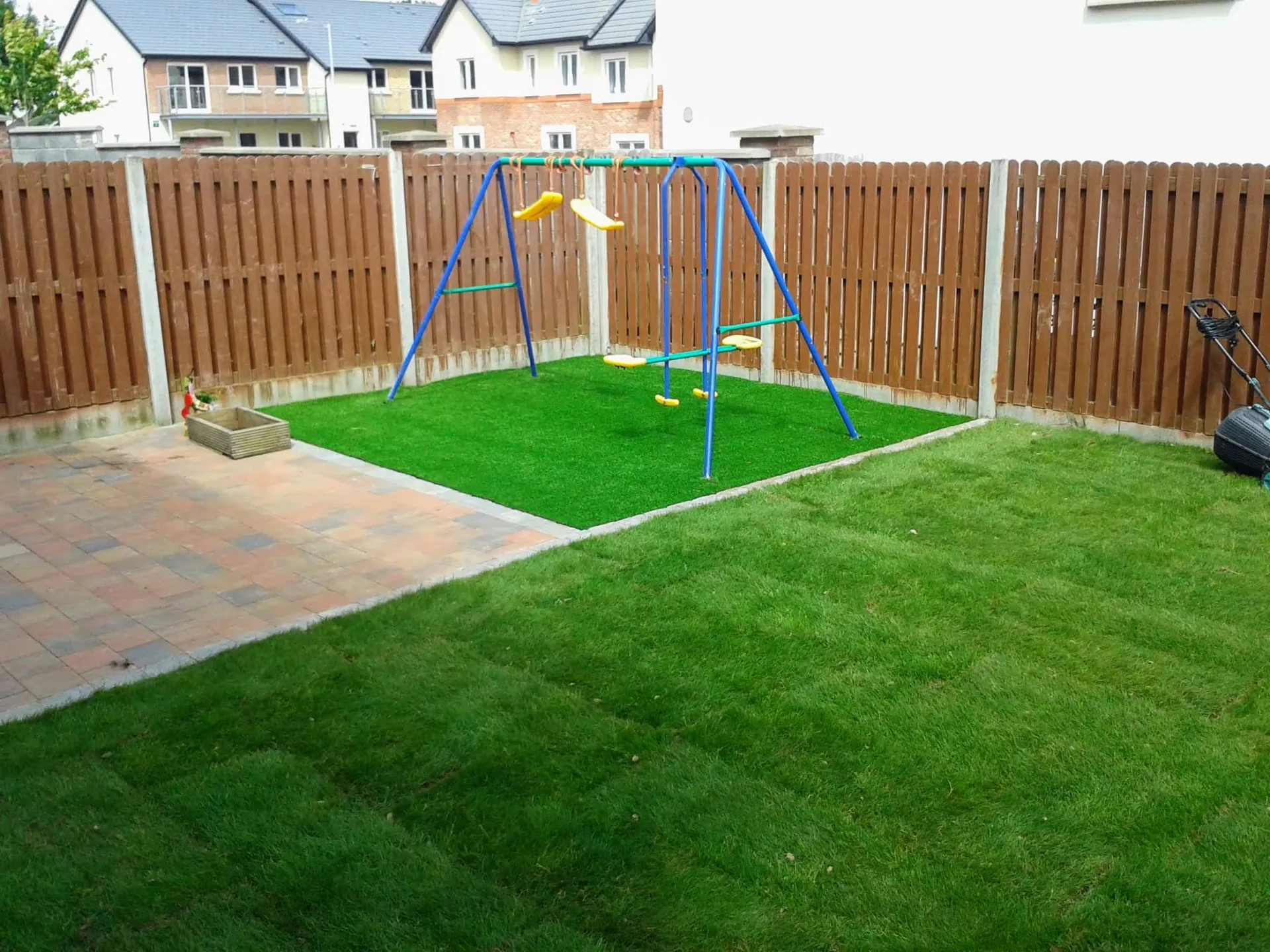 Back garden with synthetic grass play area, patio paving and natural lawn