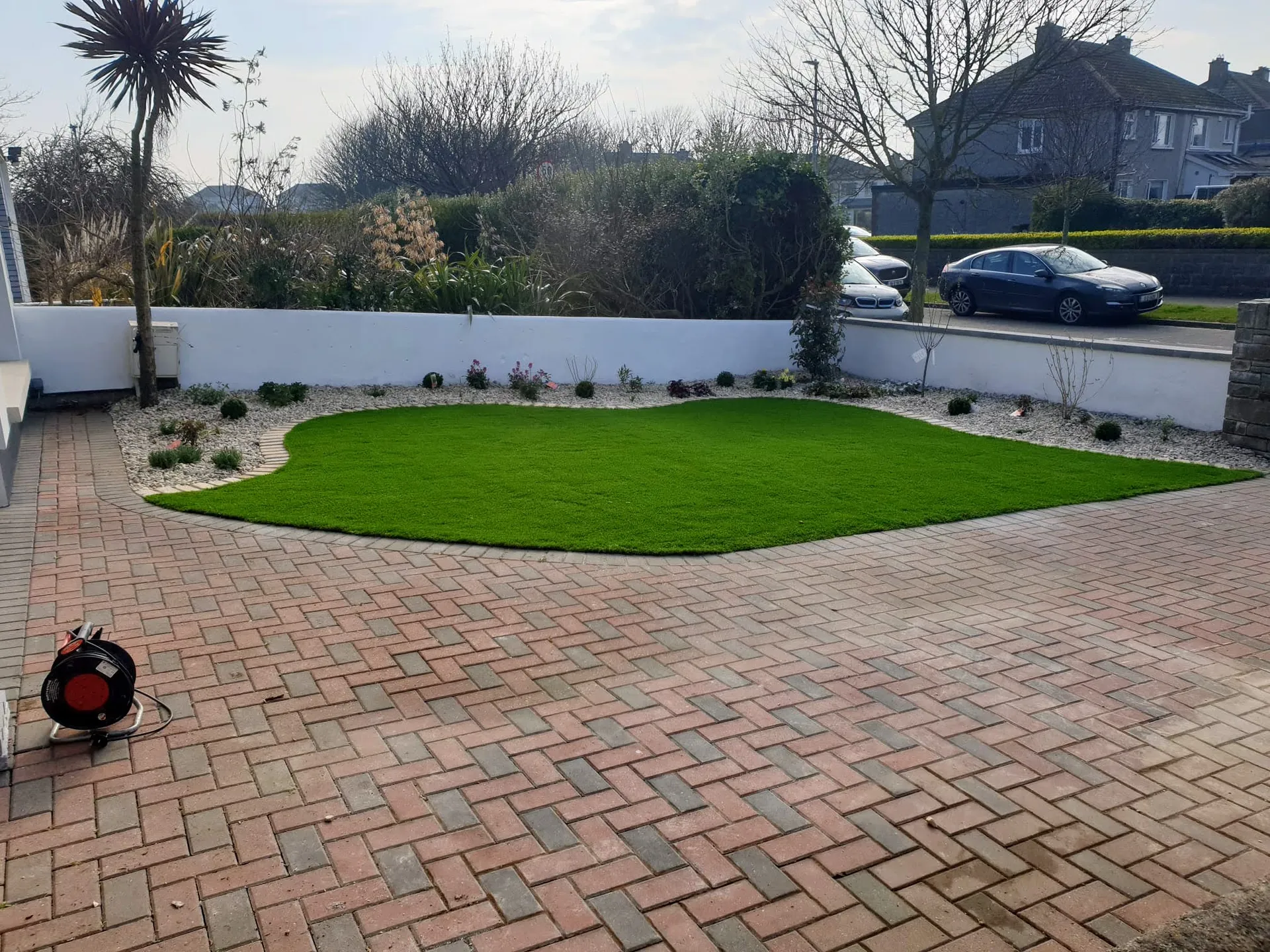 Cobblelock driveway with curved lawn and decorative planting by Mow Plus
